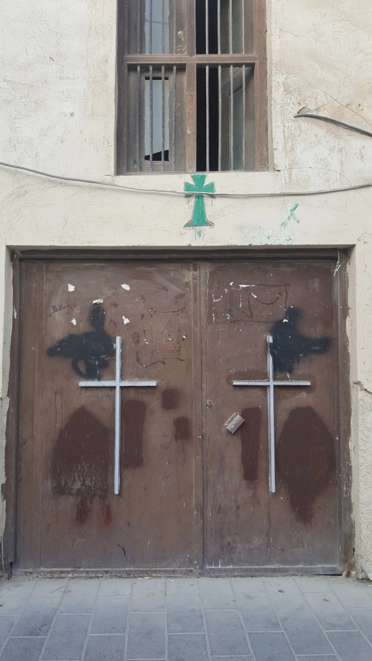 Entrance of Saint George Church in Bushehr, Iran, with cross symbols on the doors and above the doorway.