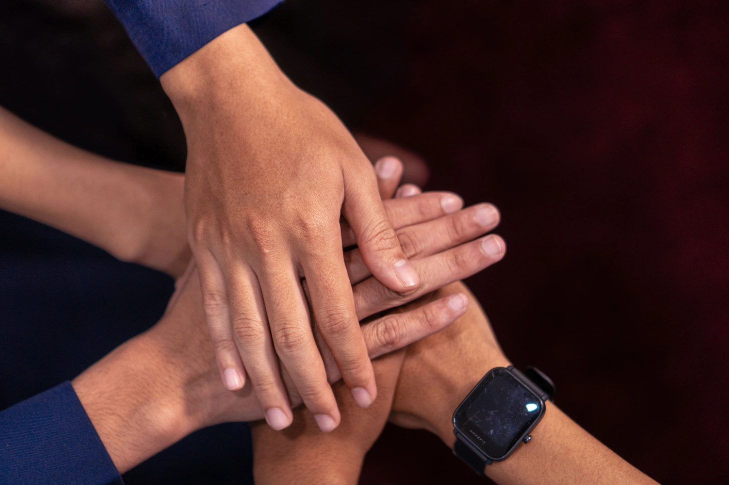 Several people placing their hands together in a gesture of teamwork and shared commitment.